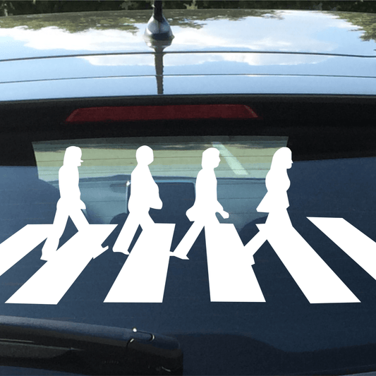 Car window with a white 'Abbey Road' decal of four figures on a zebra crossing.
