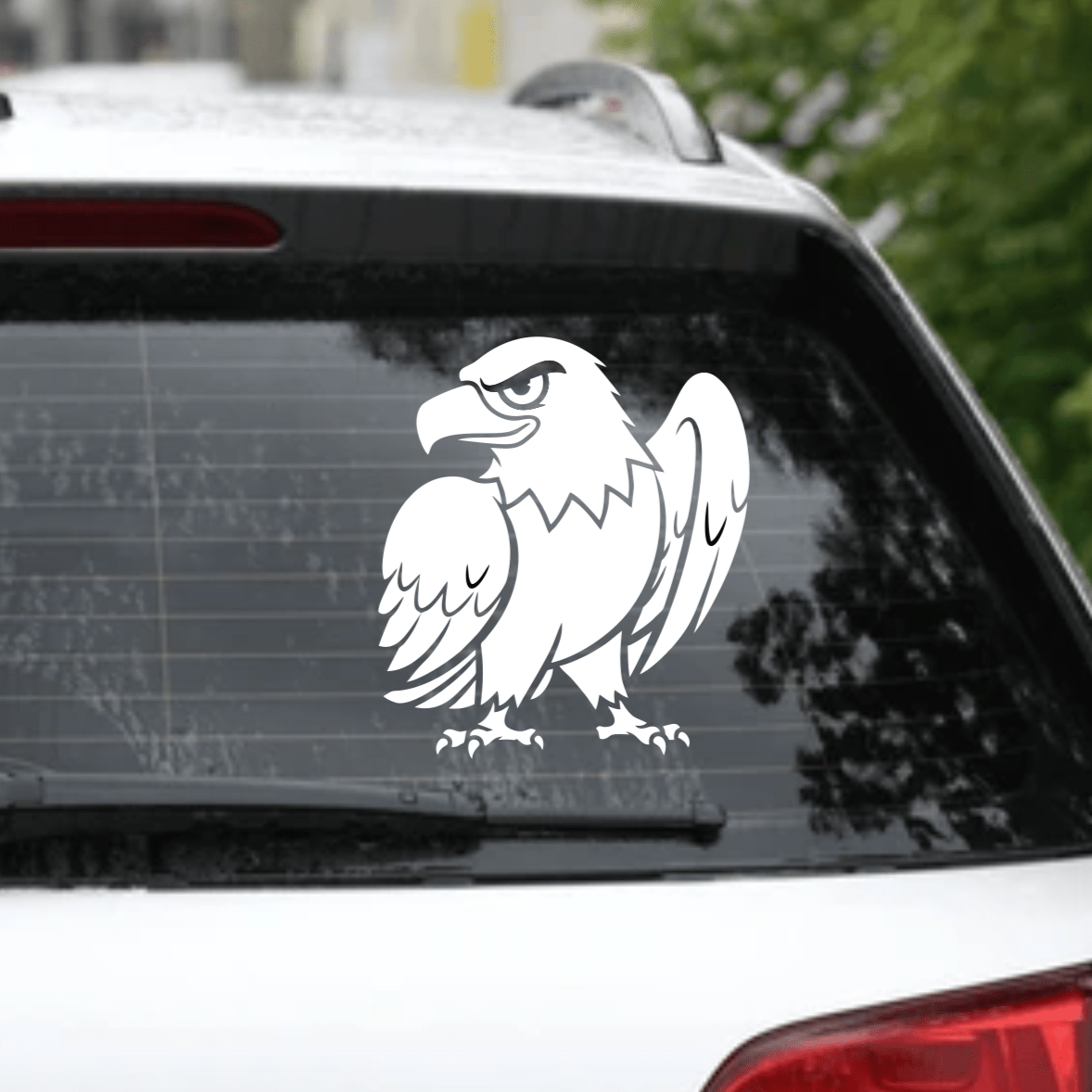 Car with an eagle decal on the rear window, parked outdoors.