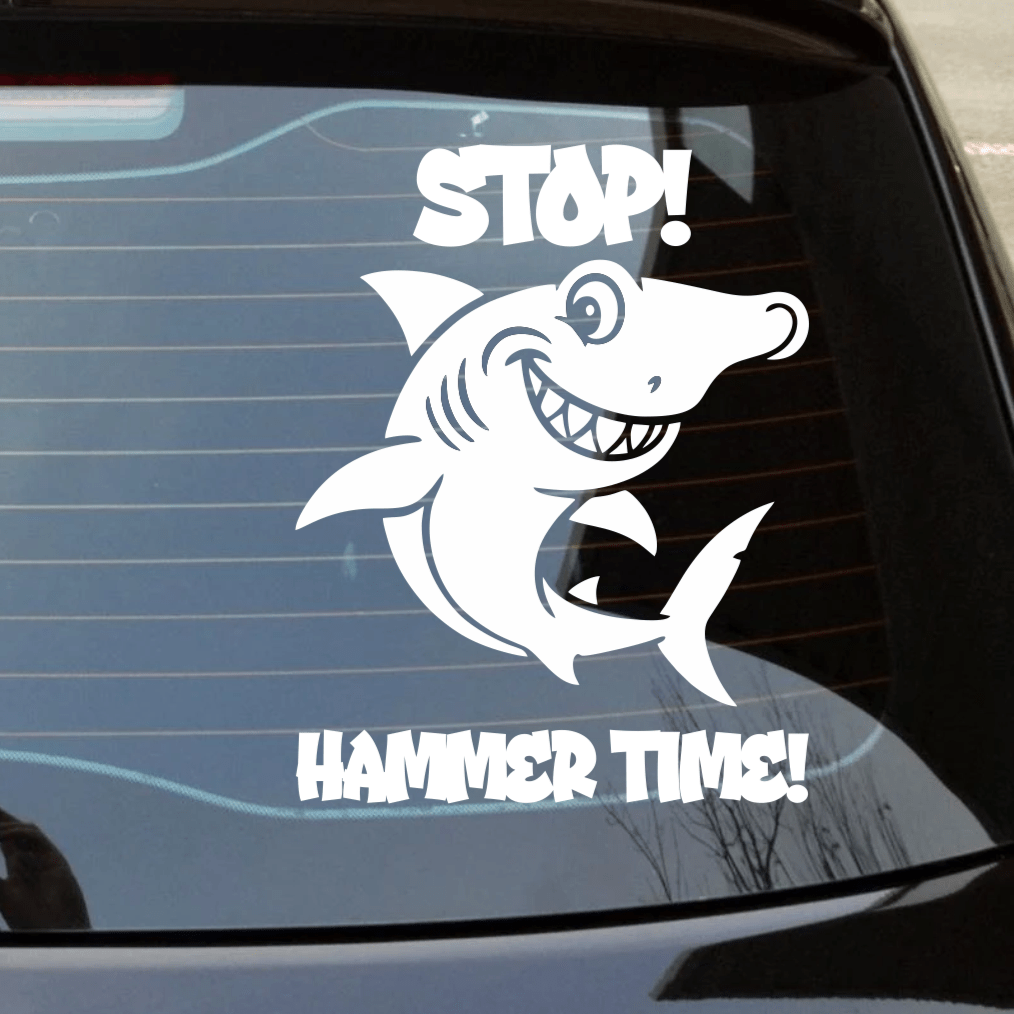 Car window with a Hammerhead shark decal and text 'STOP! HAMMER TIME!' on a street background