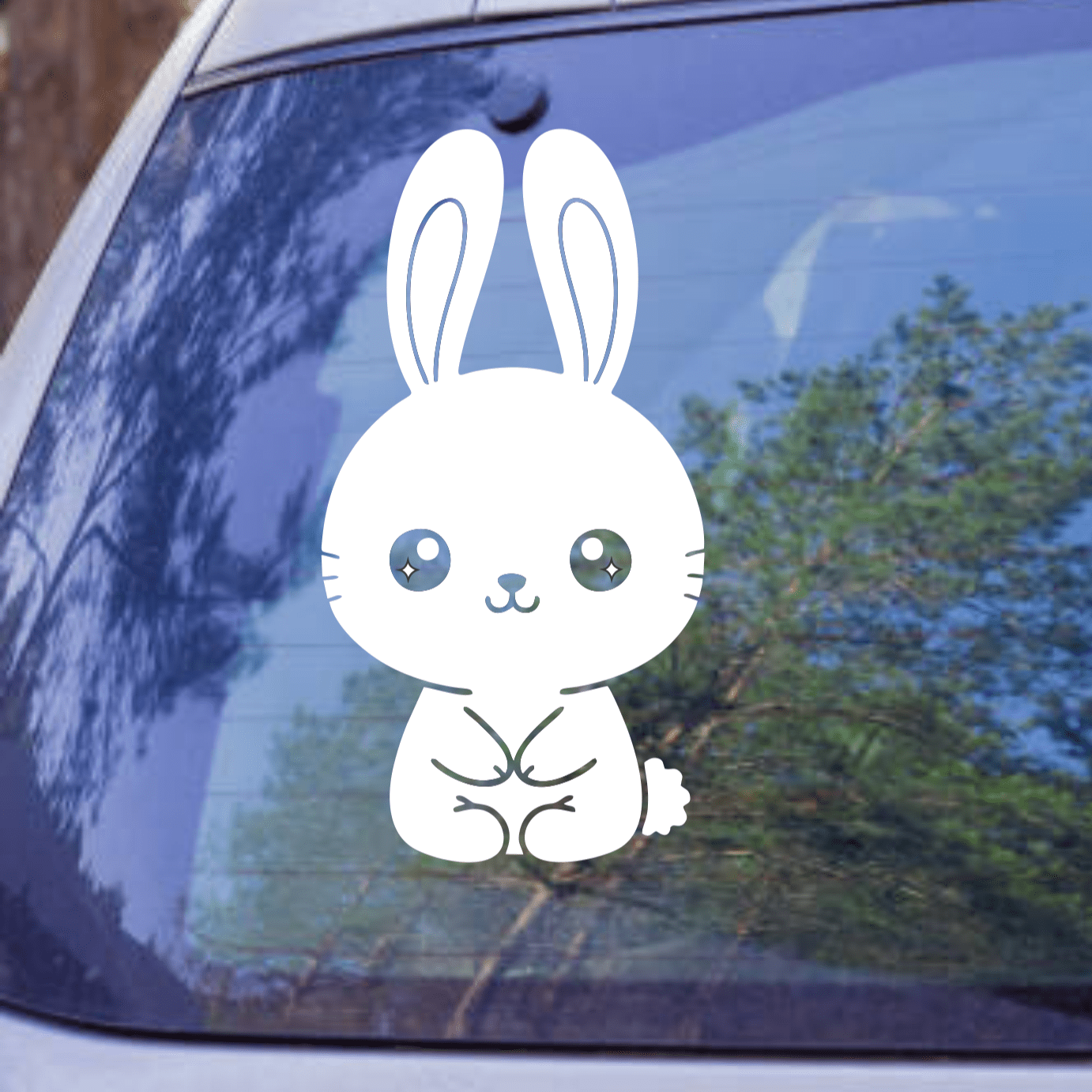 Cartoon rabbit sticker on a car window with trees in the background