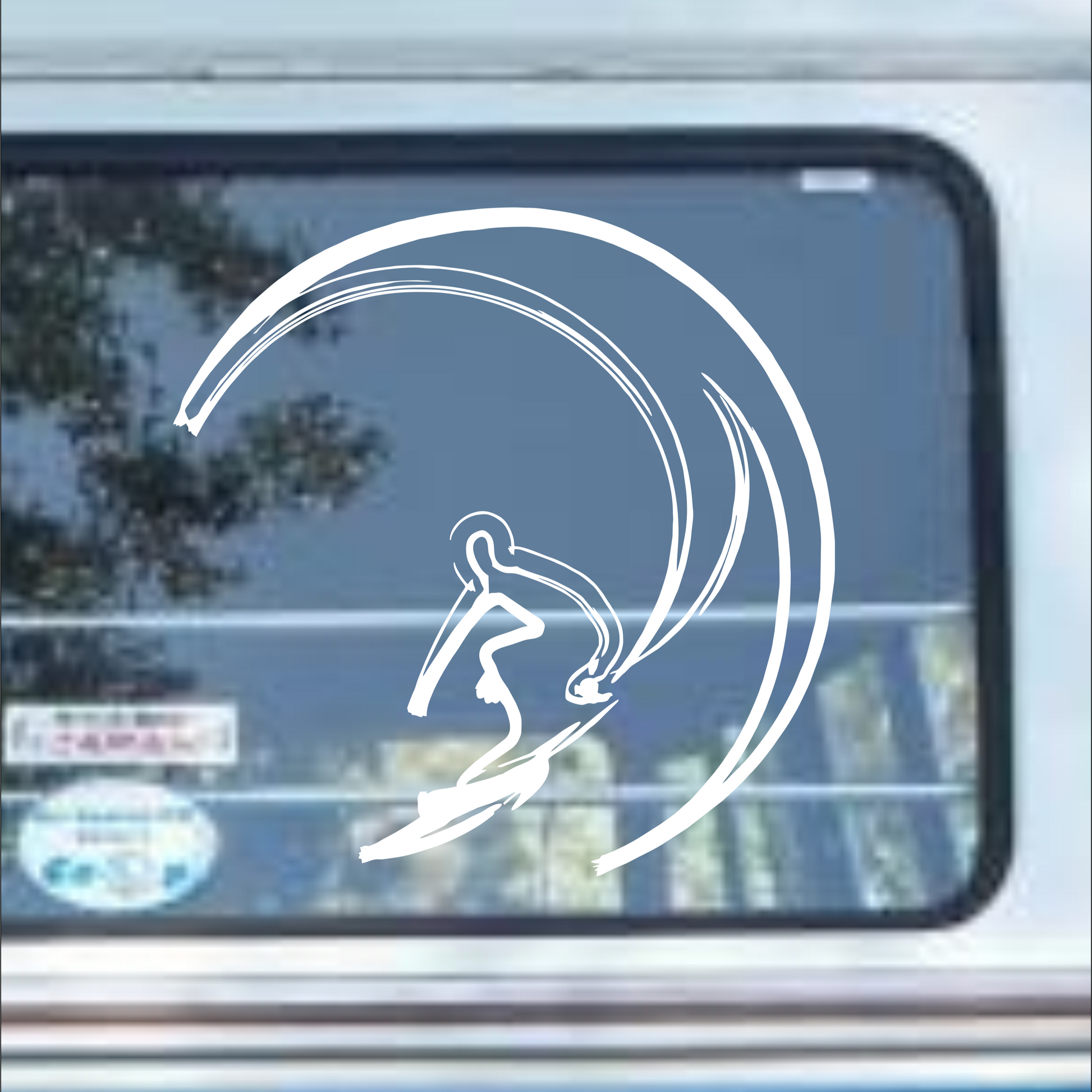 White decal of a person on a surfboard with a crescent moon on a car window.