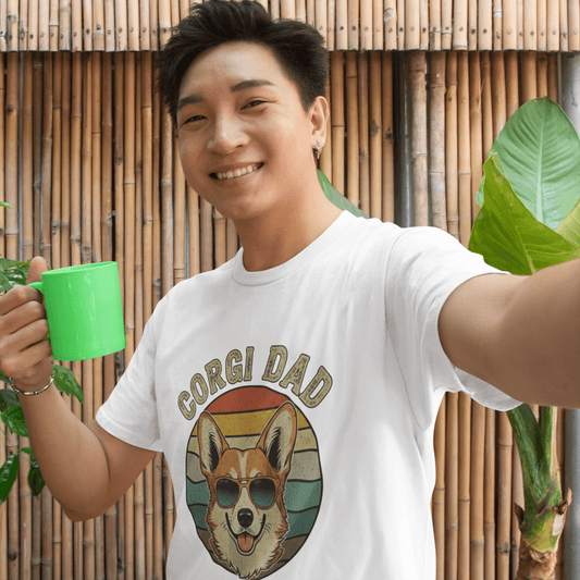 Man wearing a 'Corgi Dad' t-shirt holding a green mug outdoors.