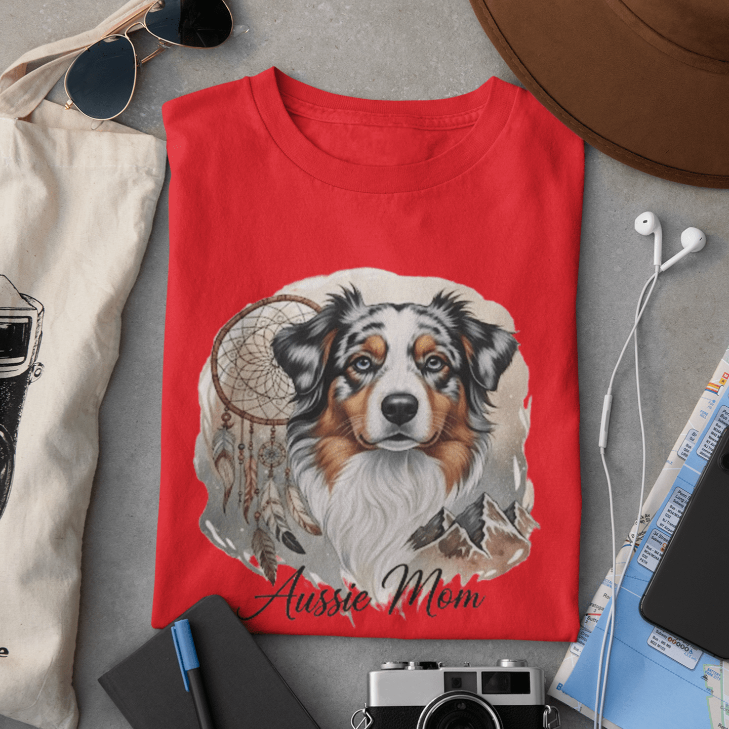 Red t-shirt with a dog illustration and 'Aussie Mom' text, surrounded by casual items on a gray surface.