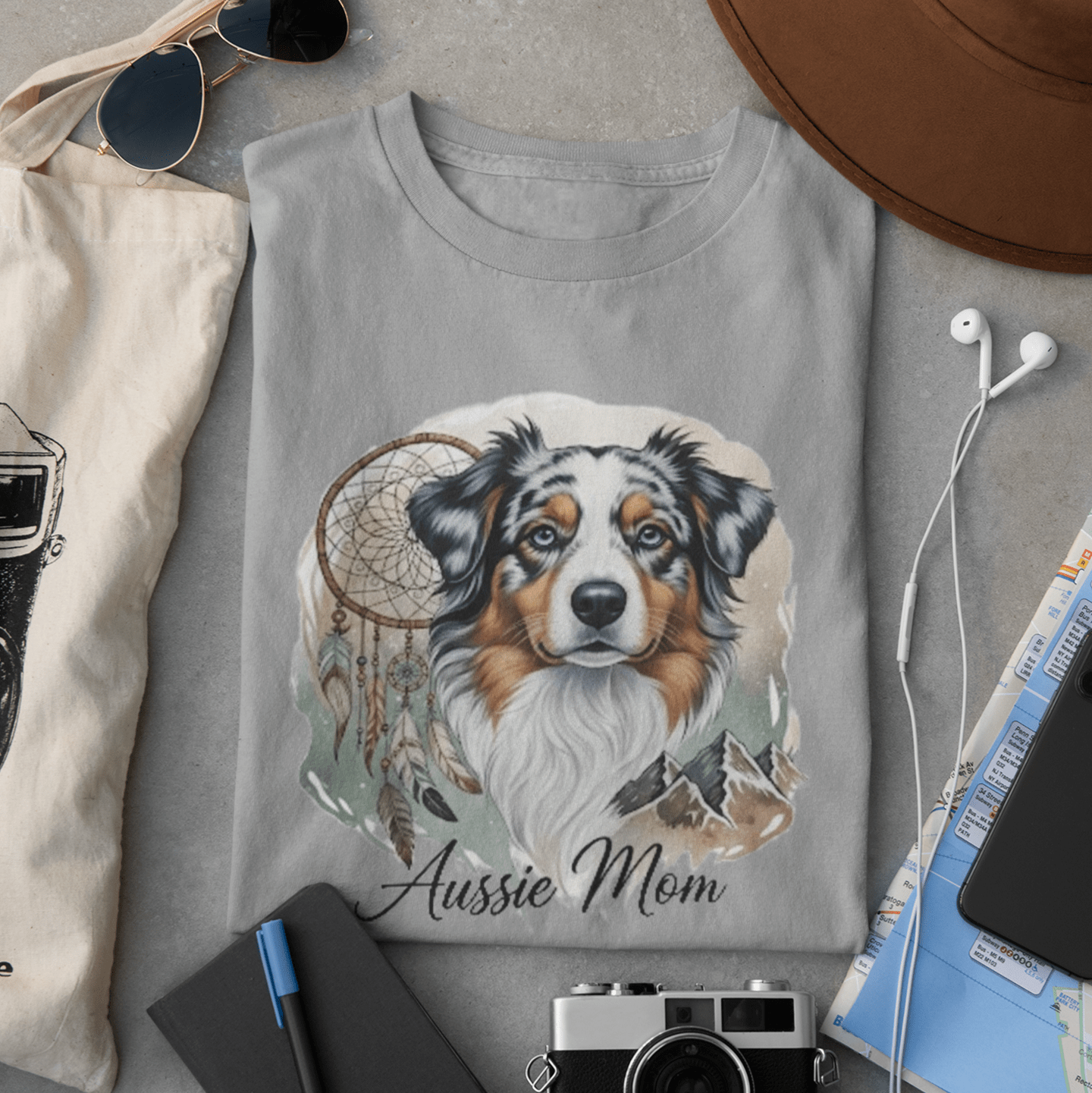 Gray sweatshirt with a dog illustration and 'Aussie Mom' text, surrounded by accessories on a gray surface.