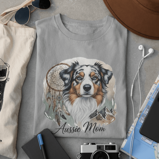 Gray sweatshirt with a dog illustration and 'Aussie Mom' text, surrounded by accessories on a gray surface.