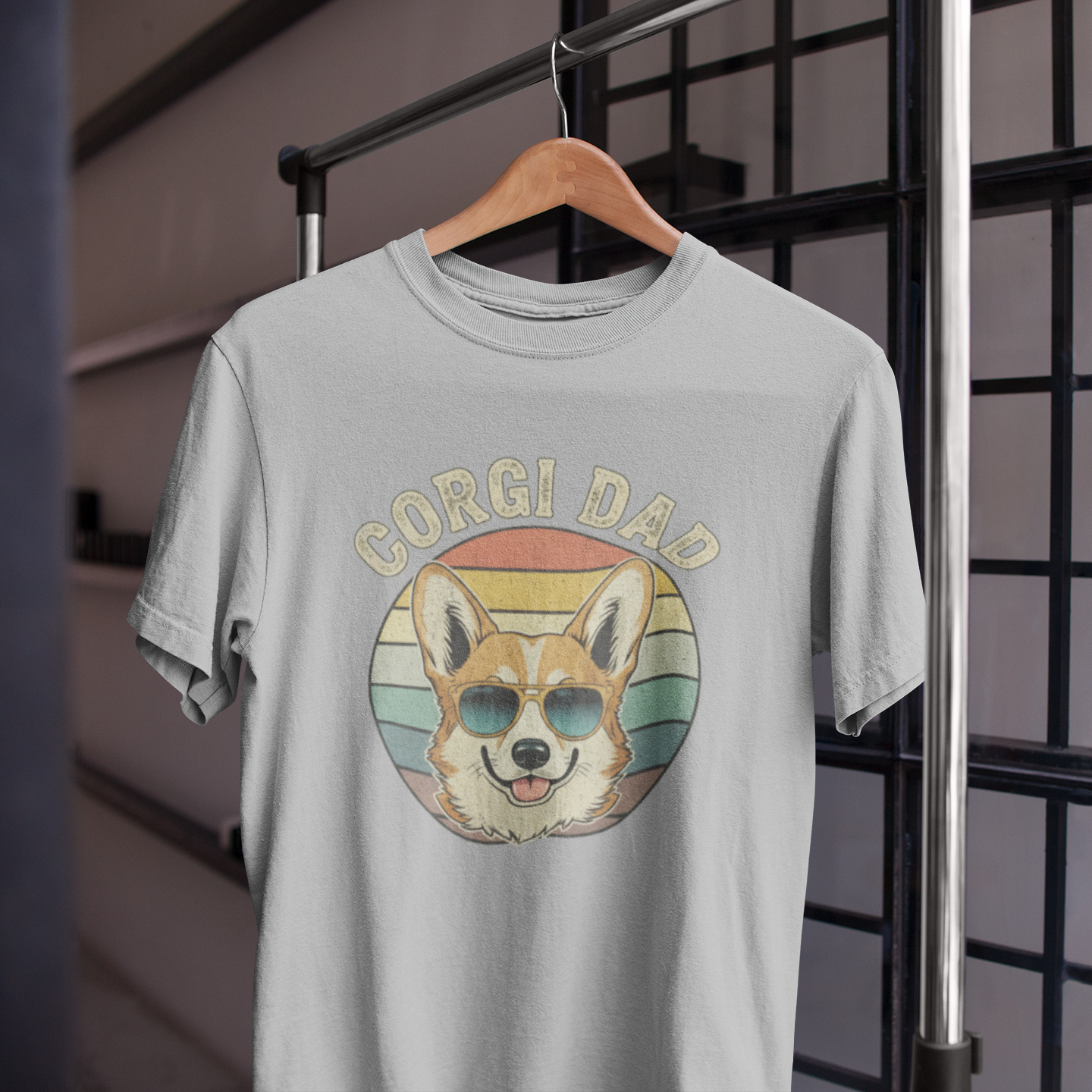 Gray t-shirt with a dog graphic and 'Gorgi Dad' text on a hanger against a grid background