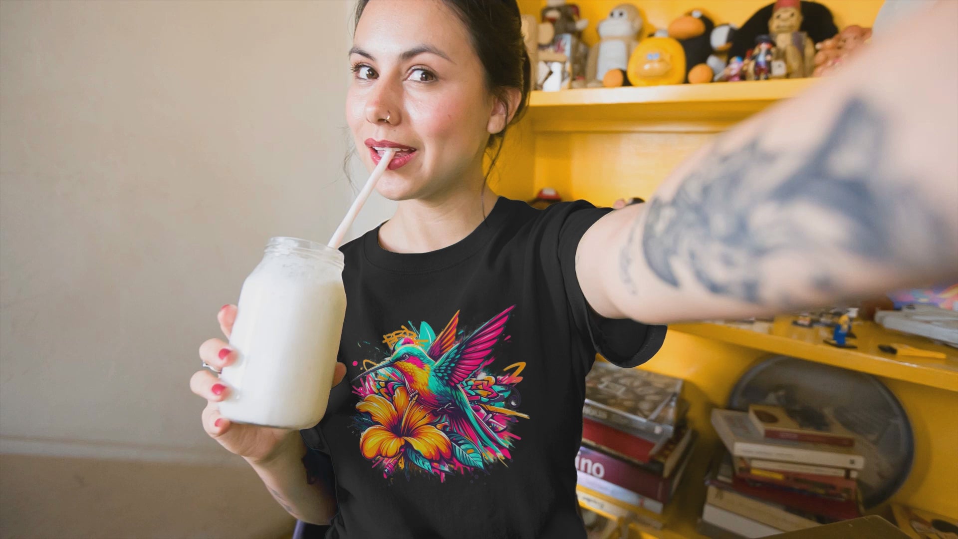 Graphic T-shirt featuring a colorful hummingbird surrounded by intricate floral designs, rendered in vibrant hues.