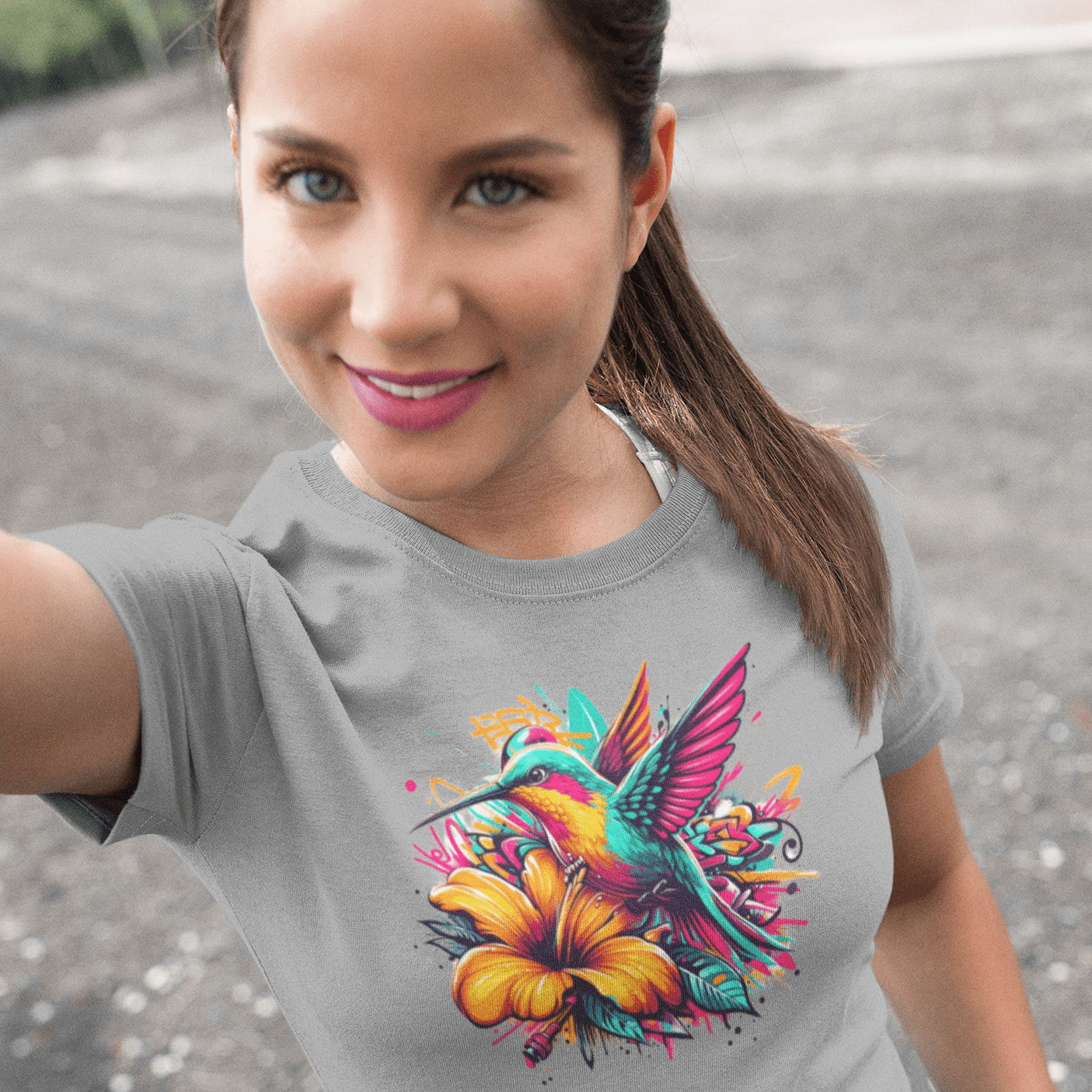 Graphic T-shirt featuring a colorful hummingbird surrounded by intricate floral designs, rendered in vibrant hues.