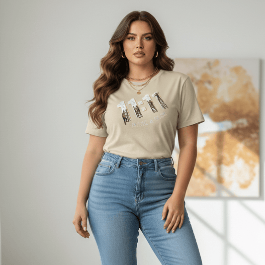 Woman wearing a beige t-shirt with 11:11 graphic design and blue jeans in a bright room.