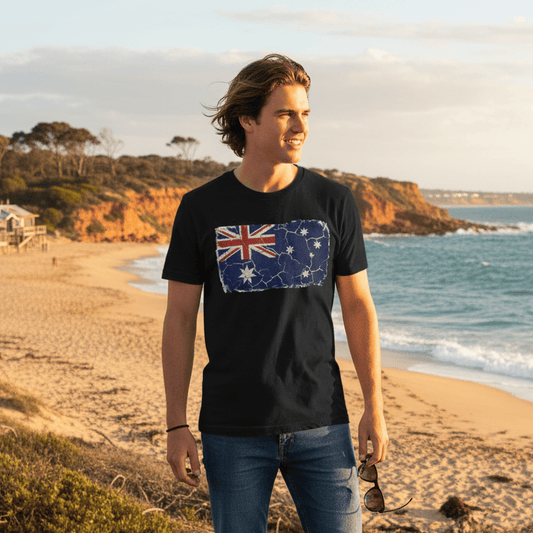 Man standing on a beach wearing a black t-shirt with an Australian flag design.