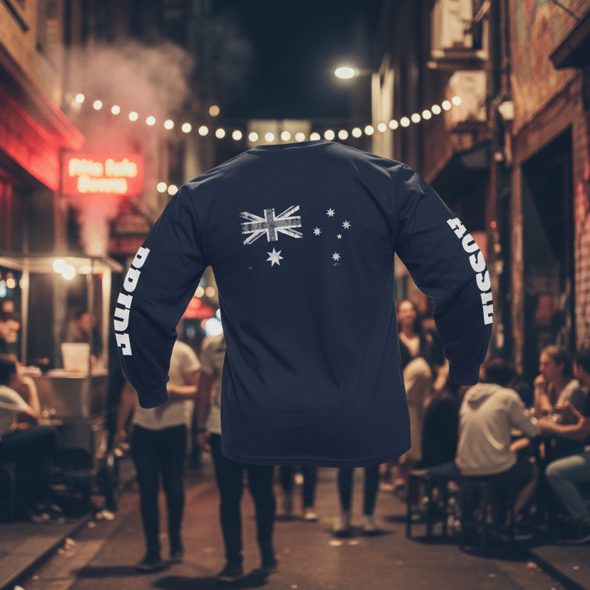 A navy blue long-sleeved t-shirt is shown from the back against a white background. Centered on the upper back is a large, distressed, monochrome print of the Australian flag in white and grey. The left sleeve features the word "PRIDE" in bold, white, vertical block lettering, while the right sleeve features the word "AUSSIE" in the same style. The shirt has ribbed cuffs and a crew neck.