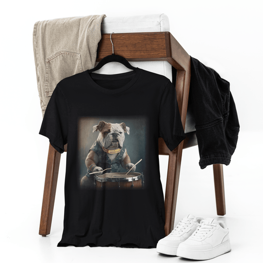 Black graphic t-shirt displayed on a hanger on a wooden chair with white sneakers and jeans, featuring an English Bulldog wearing a denim vest playing a snare drum with drumsticks.
