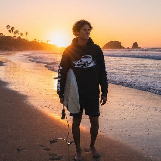Person holding a surfboard on a beach at sunset