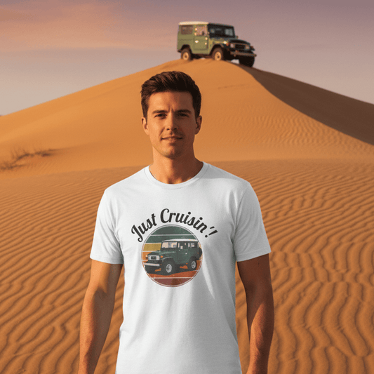 Man wearing a 'Just Cruisin!' t-shirt in a desert setting with a vehicle on a sand dune.
