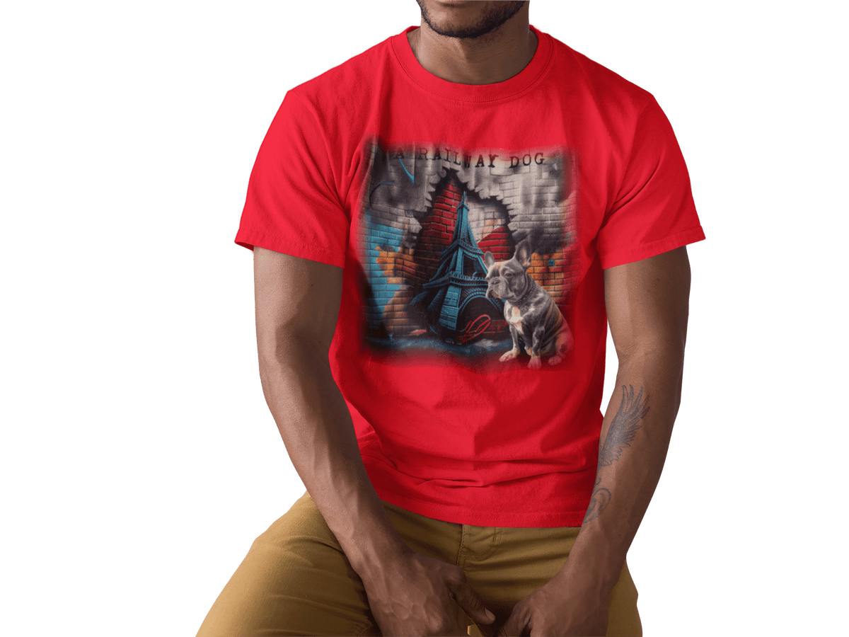 Young man wearing a bright red graphic t-shirt featuring a French Bulldog sitting in front of an urban brick wall cutout revealing the Eiffel Tower with "A Railway Dog" stencil text.