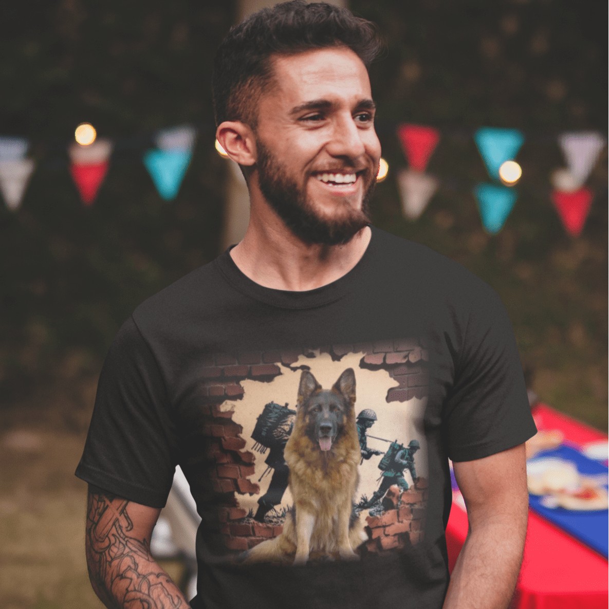 Smiling bearded man wearing a black crew-neck t-shirt featuring a detailed German Shepherd dog sitting in front of a broken brick wall graphic with soldiers in combat gear.