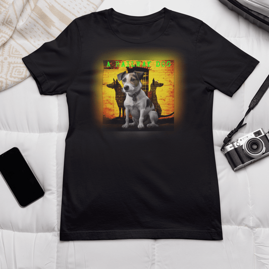 Flat-lay mockup of a black graphic t-shirt laid on a white duvet next to a vintage camera and smartphone, featuring a seated Jack Russell Terrier in front of a warm sunset-toned brick wall with dog silhouettes and "A Railway Dog" text.