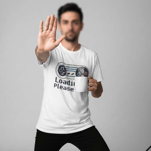 Person wearing a white Loading Please Wait t-shirt with a graphic design and text, standing against a plain background.