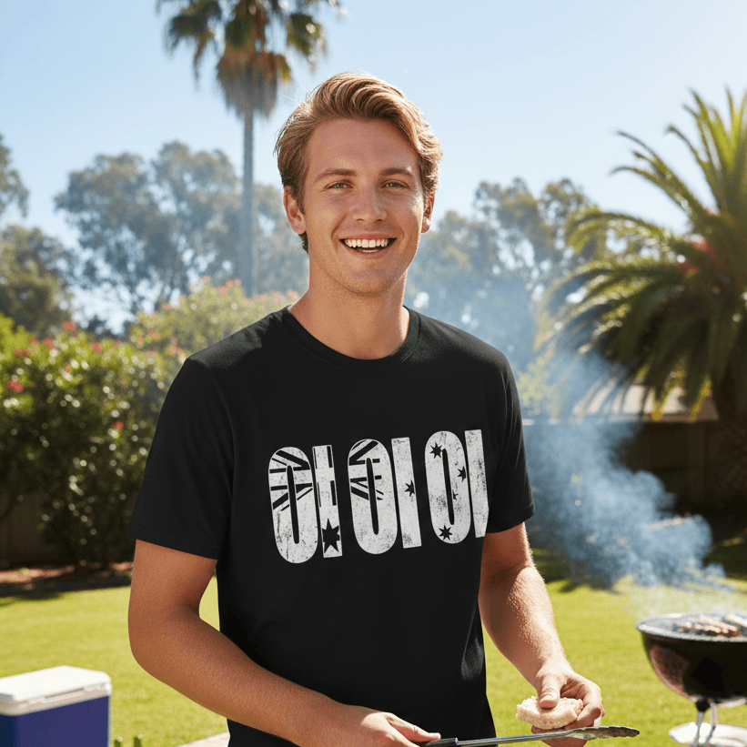 A flat-lay view of a black short-sleeved t-shirt. The center features the text "OI OI OI" in large, bold, distressed white letters. Each letter contains graphic elements of the Australian flag, including the Union Jack and the Southern Cross stars.