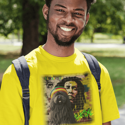 Smiling young man outdoors with a backpack wearing a bright yellow t-shirt featuring a dreadlocked Puli dog wearing a Rasta tam hat in front of a Bob Marley brick wall mural with "A Railway Dog" text.