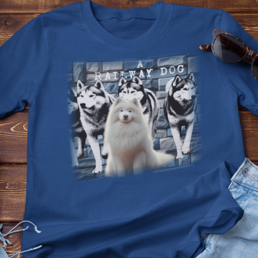 graphic t-shirt flat lay featuring a fluffy white Samoyed seated in front of a pack of Huskies against a stone wall mural with "A Railway Dog" text.