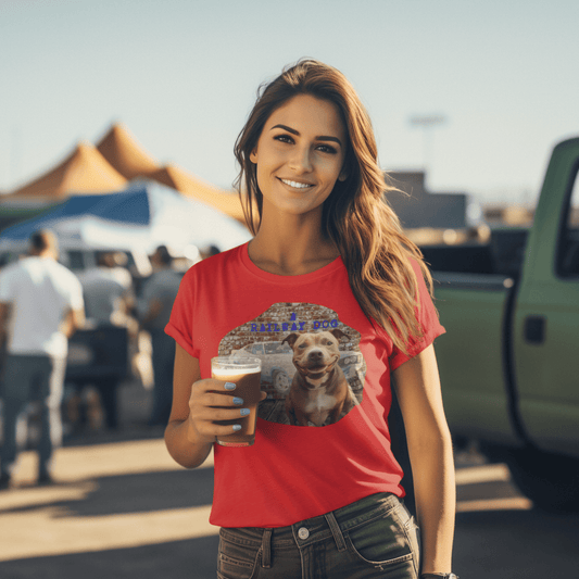 Smiling woman holding a beverage at an outdoor event, wearing a vibrant red graphic t-shirt featuring a smiling brown and white Staffy in front of a vintage muscle car mural and brick wall with "A Railway Dog" text. Staffy Cobra T-Shirt | Staffordshire Bull Terrier Ford Cobra Tee |That Should Be on a T-Shirt