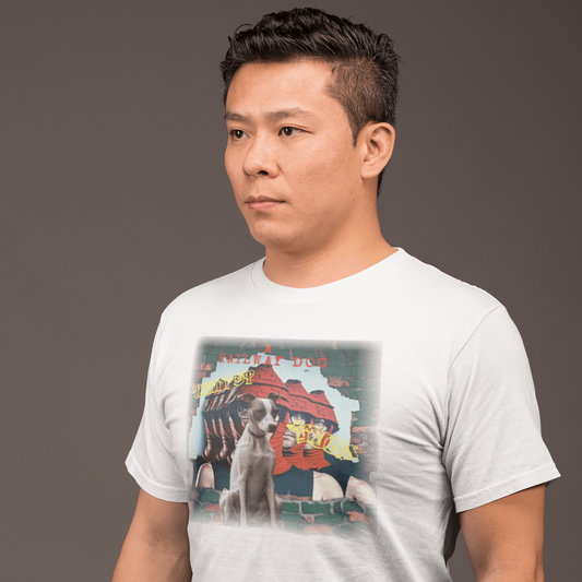 Man in profile wearing a white crew-neck t-shirt featuring a seated Whippet dog against an urban graphic print of red and green brick wall street art with "A Railway Dog" text.