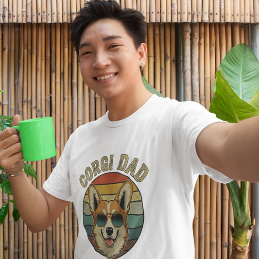 Man wearing a 'Corgi Dad' t-shirt holding a green mug outdoors.