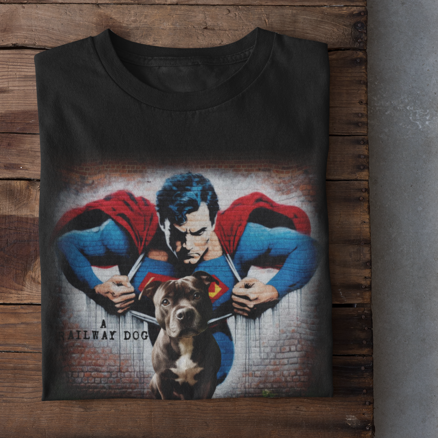 Graphic T-shirt featuring a playful Staffordshire Bull Terrier in a Superman costume, with a bold and colorful comic book style design.