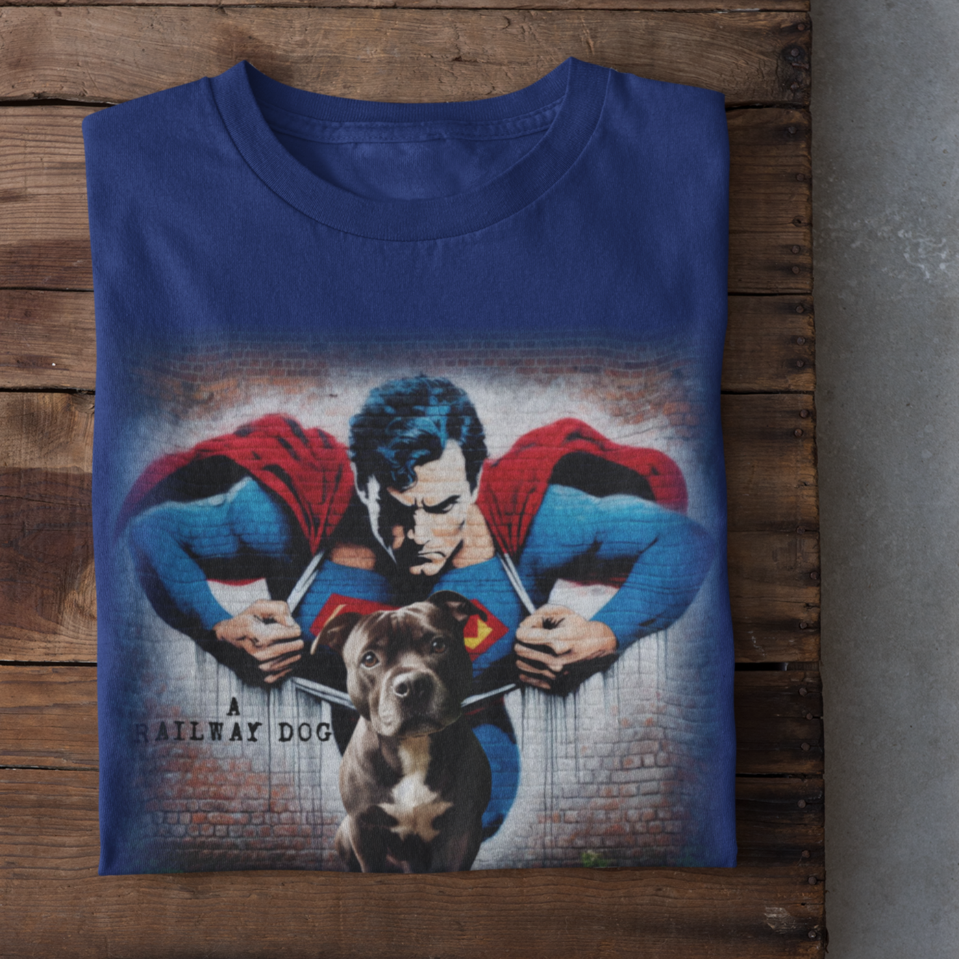 Graphic T-shirt featuring a playful Staffordshire Bull Terrier in a Superman costume, with a bold and colorful comic book style design.