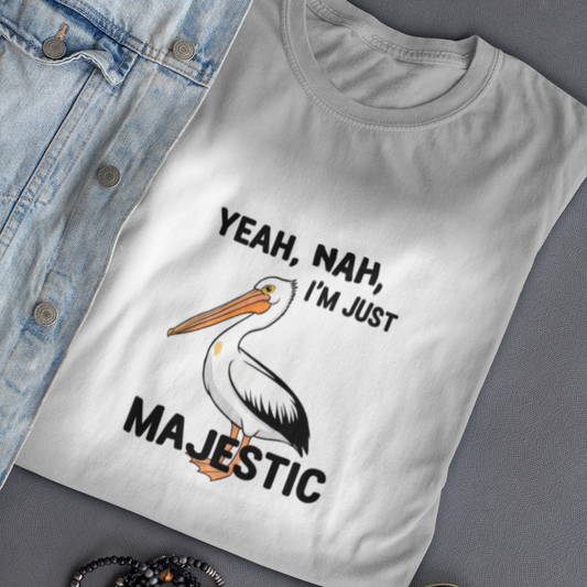 White t-shirt with a pelican graphic and text on a gray surface with denim jacket, sunglasses, and bracelets.