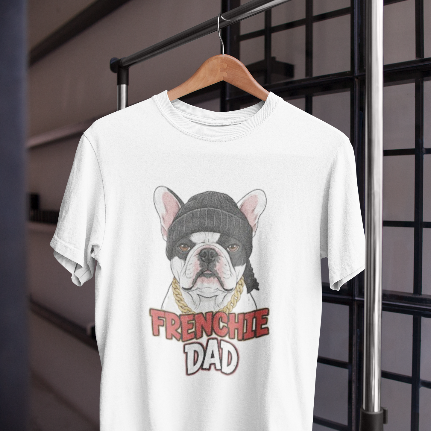 White t-shirt with a graphic of a bulldog wearing a beanie and 'FRENCHIE DAD' text on a hanger.