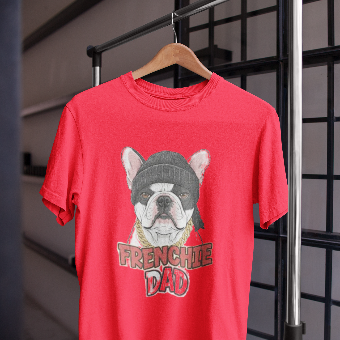 Red t-shirt with a dog graphic and 'FRENCHIE DAD' text on a hanger against a grid background