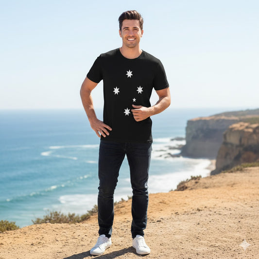 Man wearing a black t-shirt with the Southern Cross designs standing on a cliff overlooking the ocean.